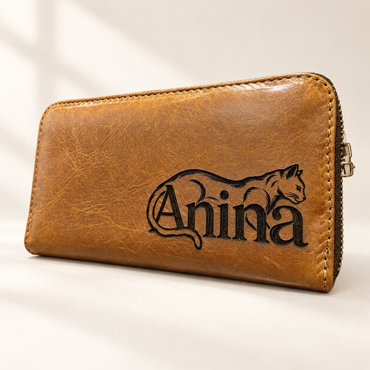 Tan leather zip clutch engraved with a cat illustration and the name Anina.